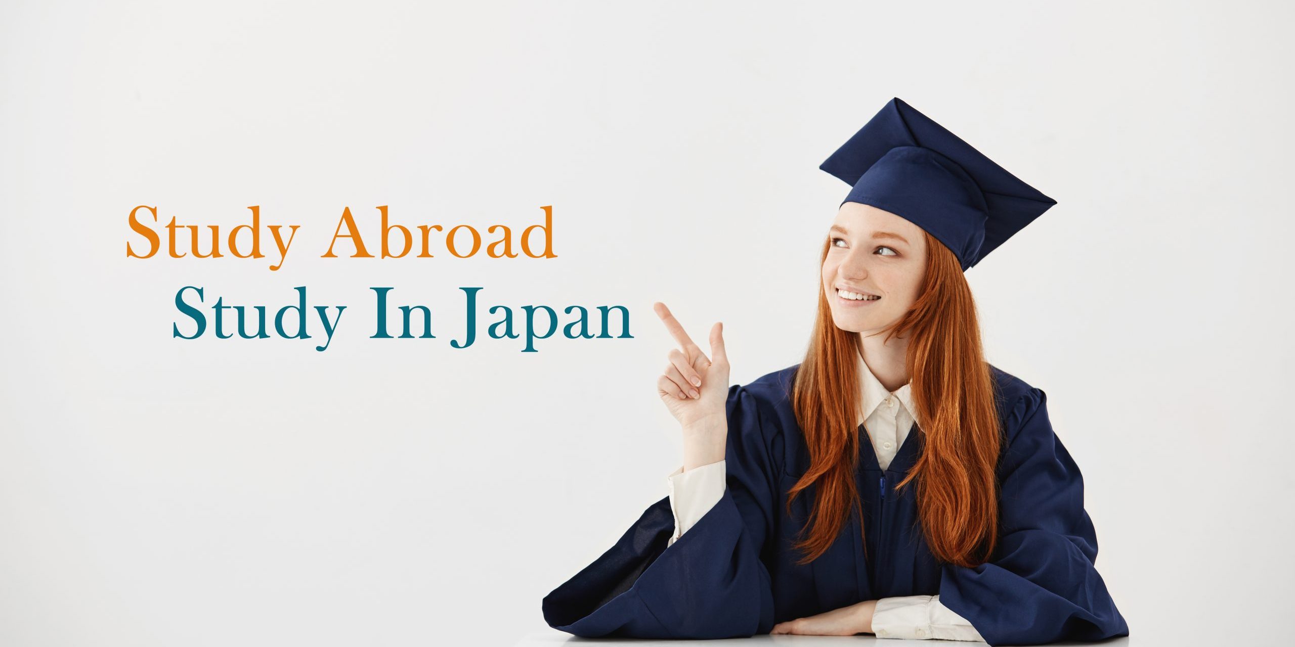 Young female university graduate in academic cap sitting at table smiling pointing left. Future lawyer or engineer showing an idea. White background.